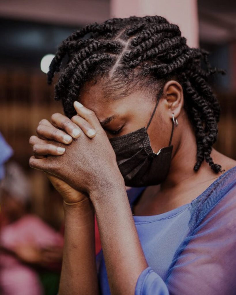 A woman praying during a Mark Odeke Ministries service