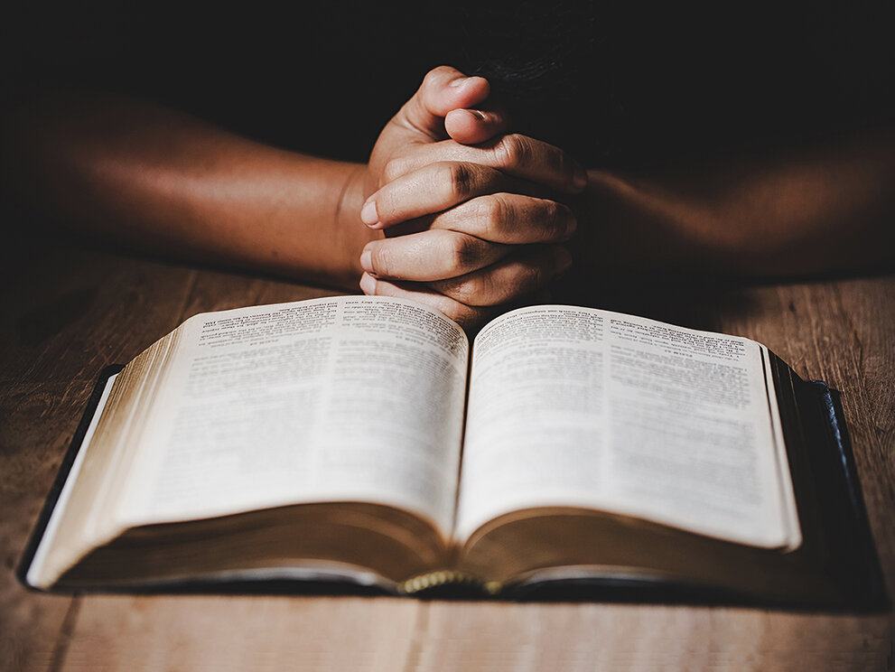 Hands folded over an open Bible